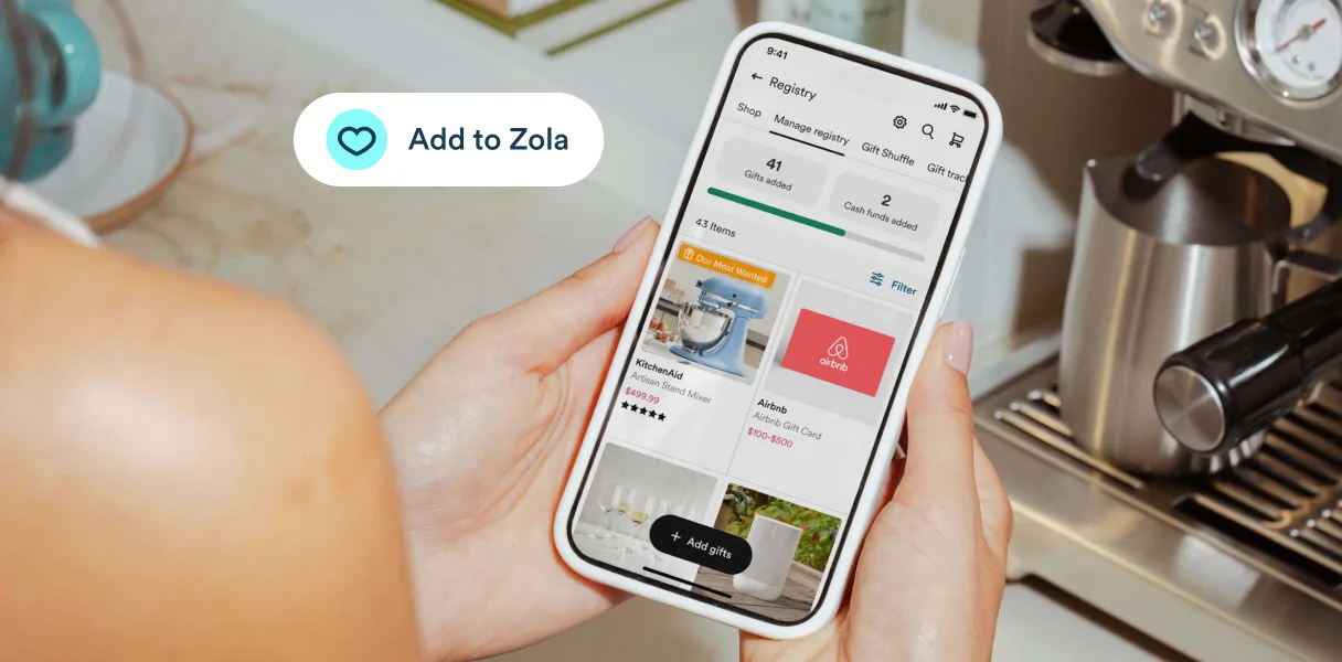 Hands holding a phone showing a Zola registry, with an Add to Zola button over a kitchen espresso machine