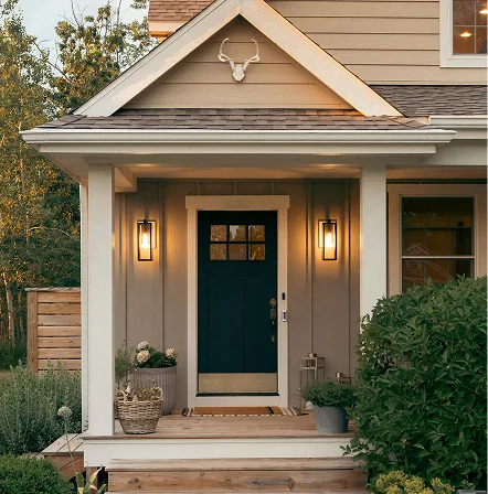 A lit front porch of a cottage at dusk with a dark teal front door