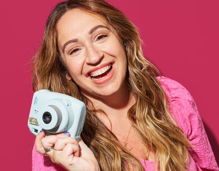 Melissa smiling and holding up a camera